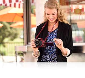 Nikon D5500 photo of a woman looking at the LCD of her D5500, highlighting its compact size and design