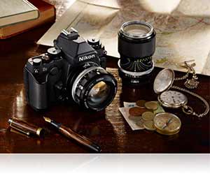 Photo of the Nikon Df and older NIKKOR lenses among items on a desk highlighting compatibility with legacy lenses