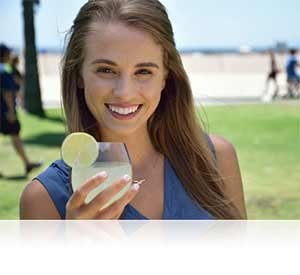 Nikon D5300 photo of a woman with a cold drink in her hand, on a beach showing a comfortable size.